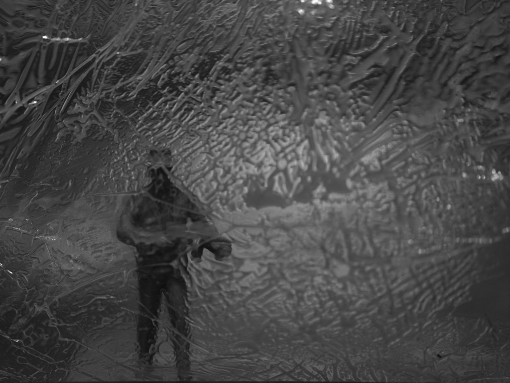 Monochrome figure obscured by a heavily textured translucent surface