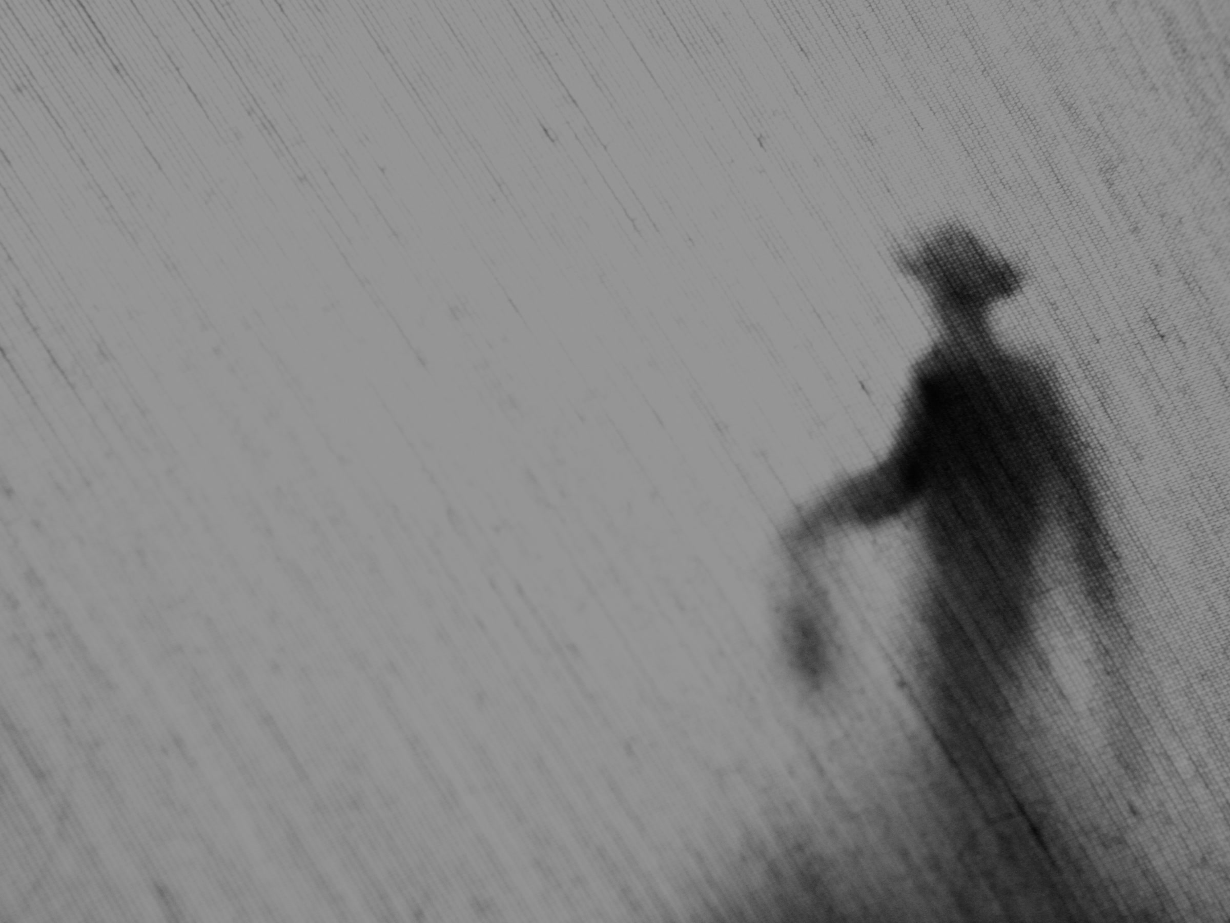 Hazy monochrome figure behind a streaked translucent surface