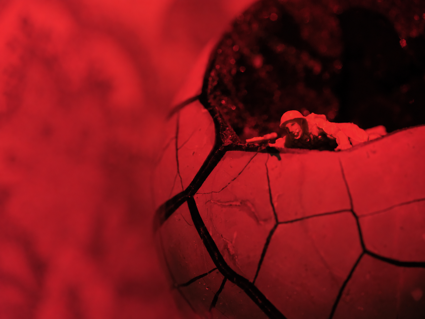 Red-lit miniature figure seen through a fractured translucent structure